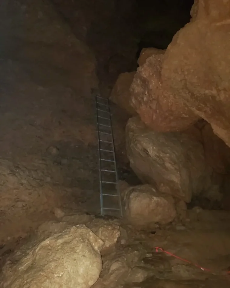 Metal ladder beside limestone rock inside ATM Cave